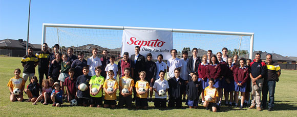 Maffra and Leongatha football teams line up with Saputo employees before the ‘grudge match’ on Maffra ground. 
